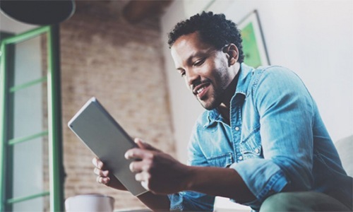 Man sitting down and looking at a tablet he is holding